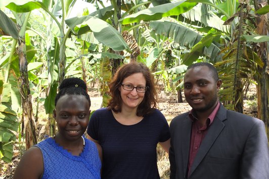 Three People posing and smiling for a photograf in teh midst of tropical plants