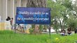 Blue information sign standing in the lawn in front of a building