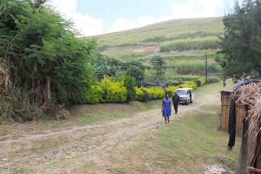 Two people and a car in green and hilly landscape