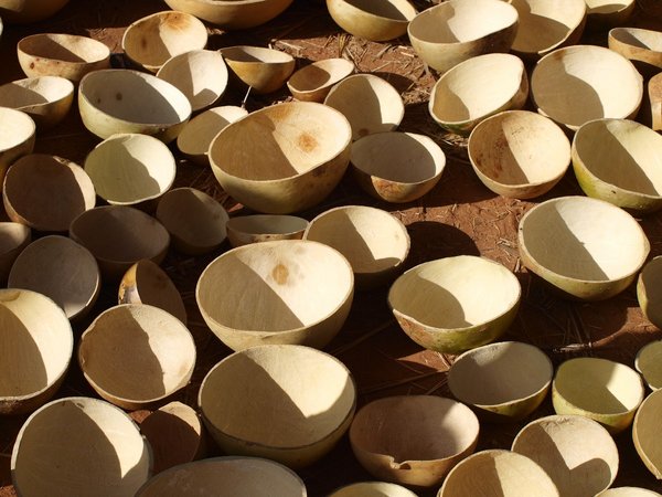 numerous crafted beige bowls made of natural materials standing on the brown ground