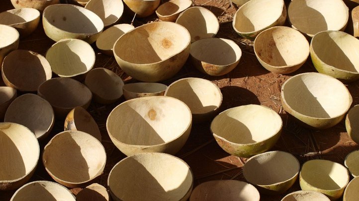 numerous crafted beige bowls made of natural materials standing on the brown ground