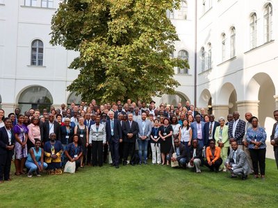 Ein Gruppenfoto in einem Innenhof. Die Mitarbeiter von Afrika-UniNet stehen auf einer Wiese, bei Sonnenschein.